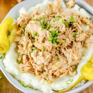 white bowl filled with mashed potatoes and shredded Mississippi chicken