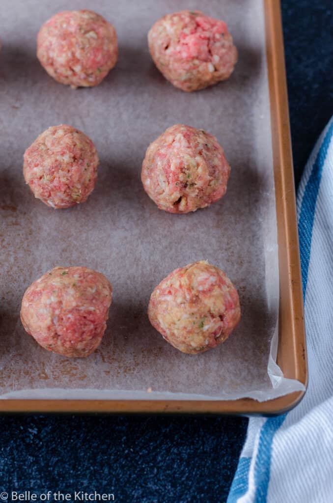 uncooked meatballs on a sheet pan