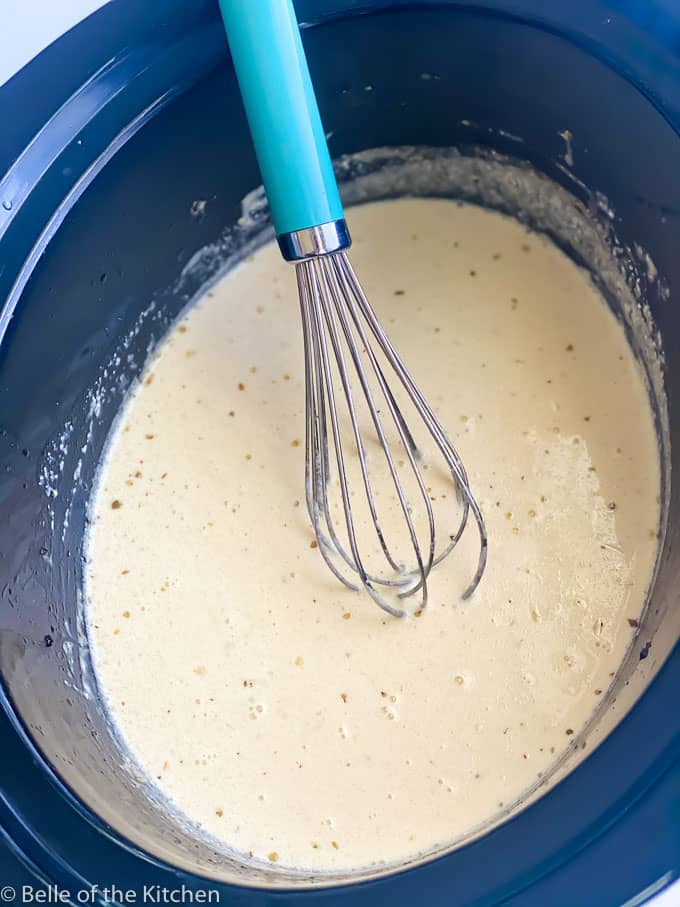 Alfredo sauce in a crockpot with a whisk
