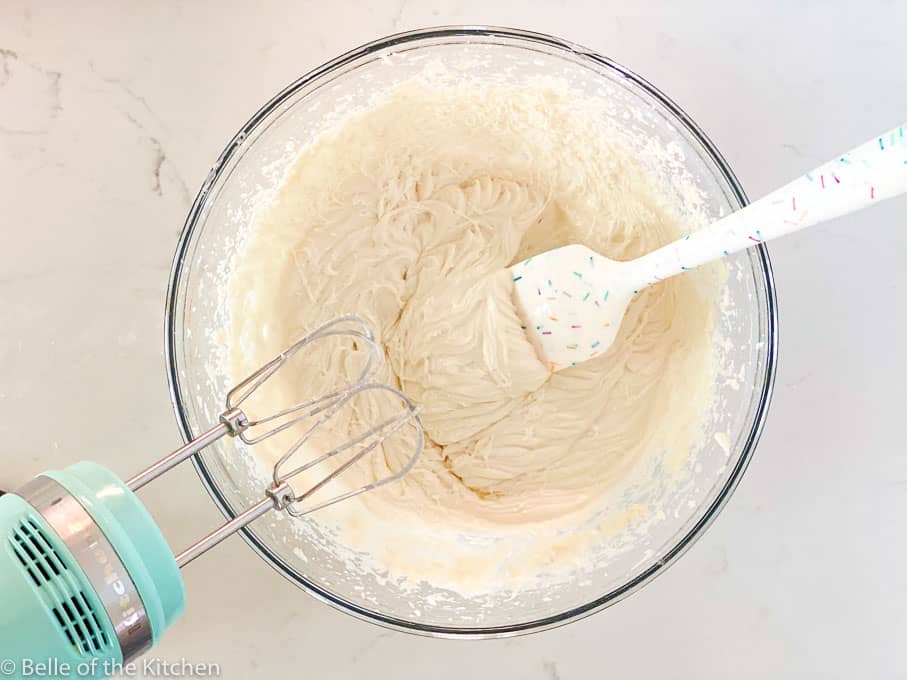 a glass bowl with a spatula and frosting