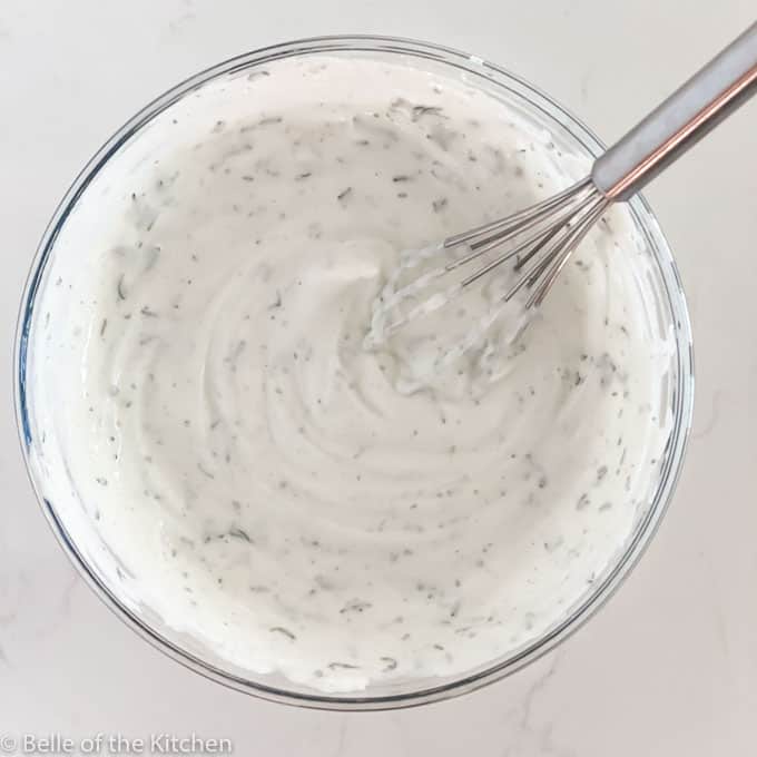 a glass bowl of dip with a whisk