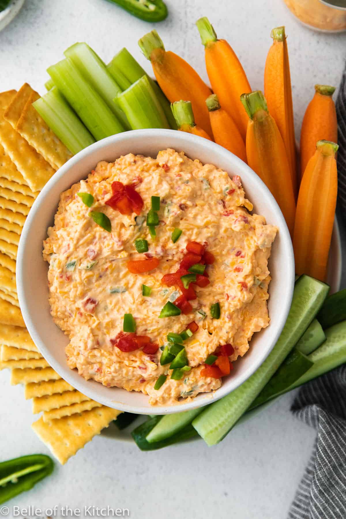 a bowl of pimento cheese with crackers and veggies around it