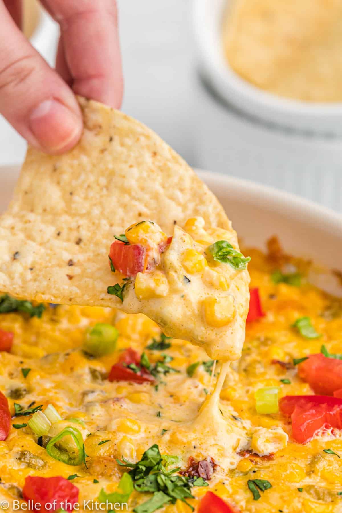 a chip scooping up cheese dip with corn