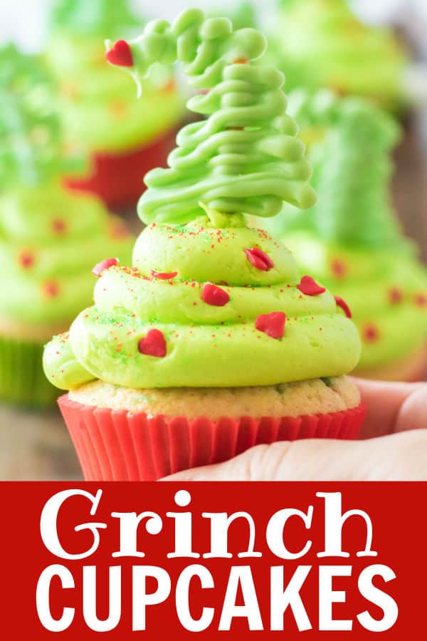a hand holding a grinch cupcake with a pretzel tree on top