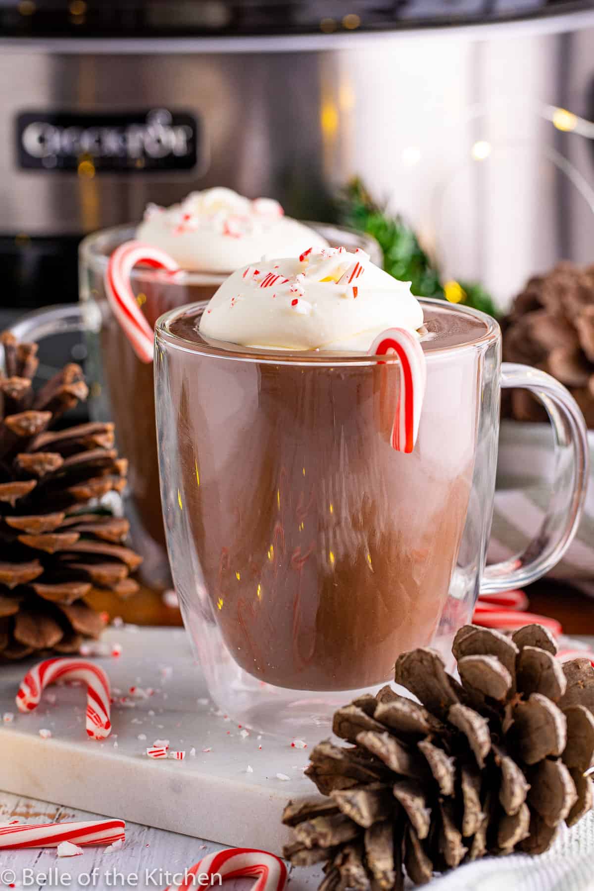 mugs of hot chocolate next to pine cones