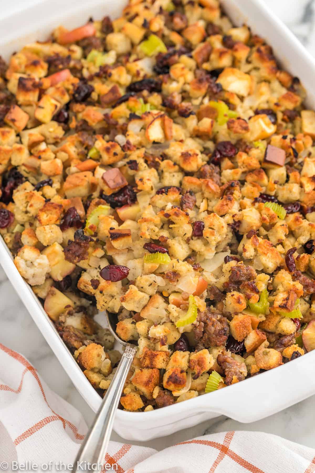 apple sausage stuffing in a baking dish with a spoon