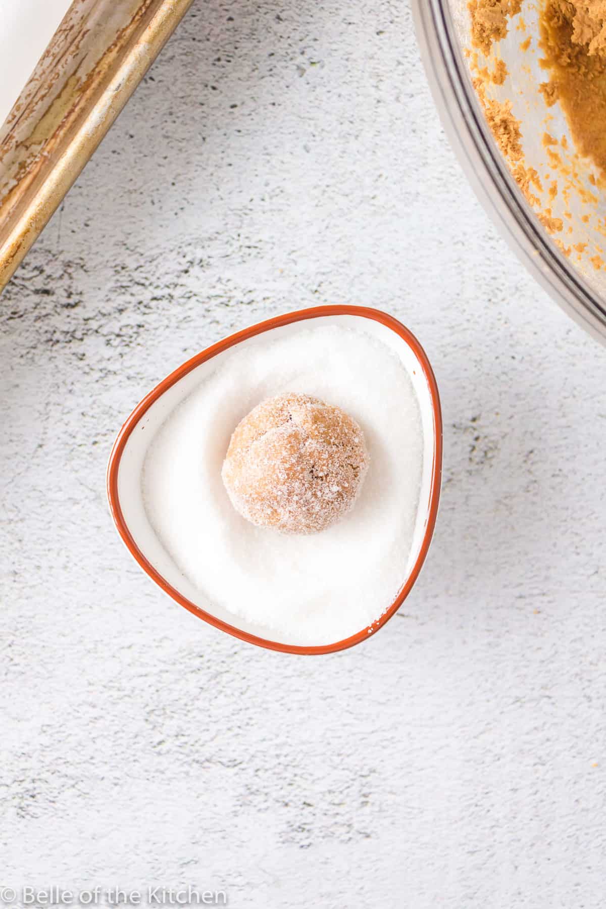 a dough ball in a bowl of sugar