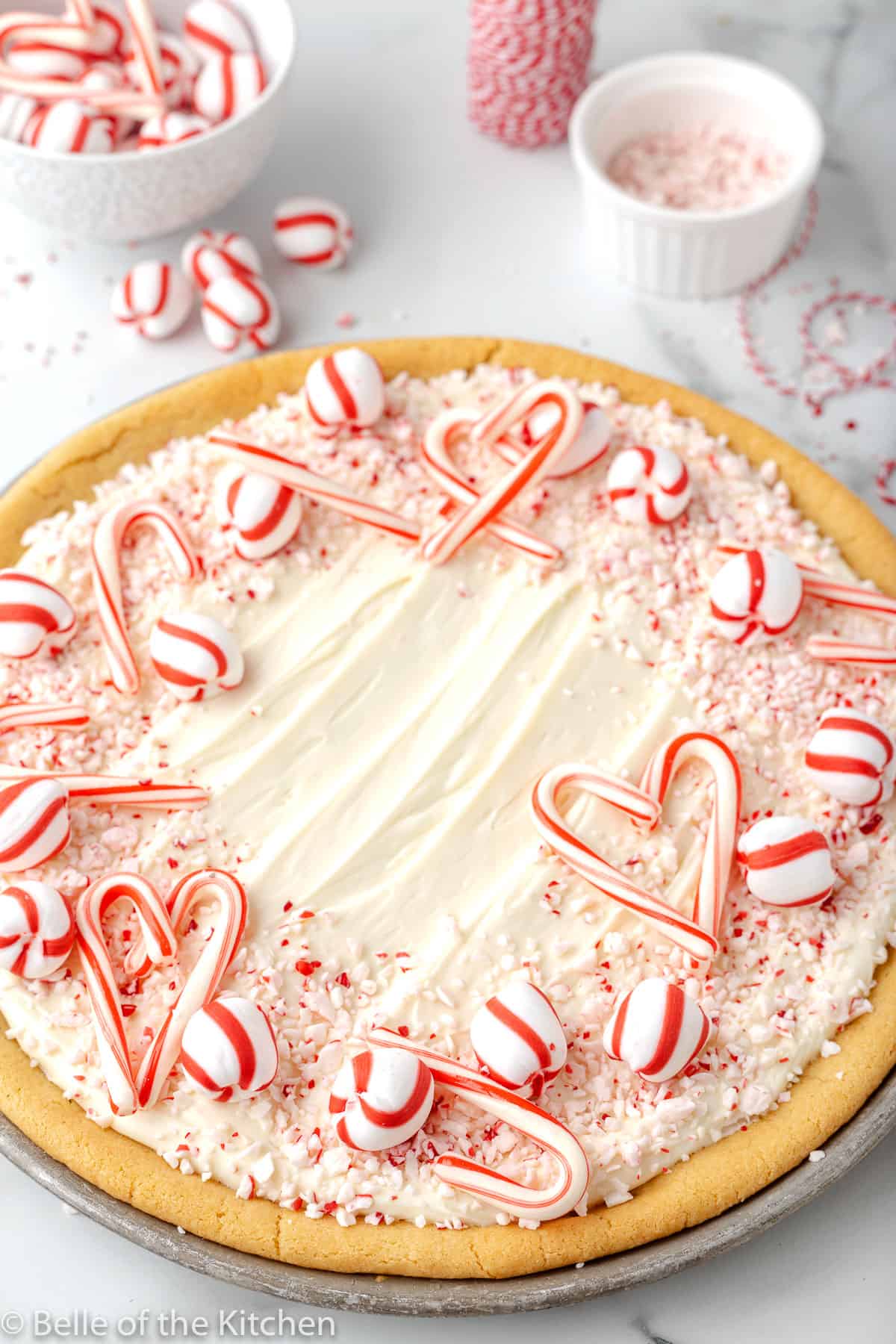 a peppermint cookie pizza with frosting and candy canes