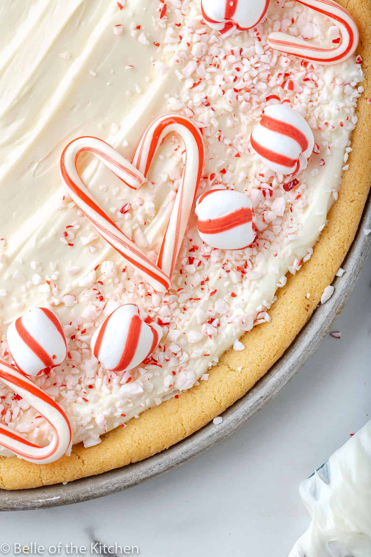 a cookie pizza with vanilla frosting and candy canes on top