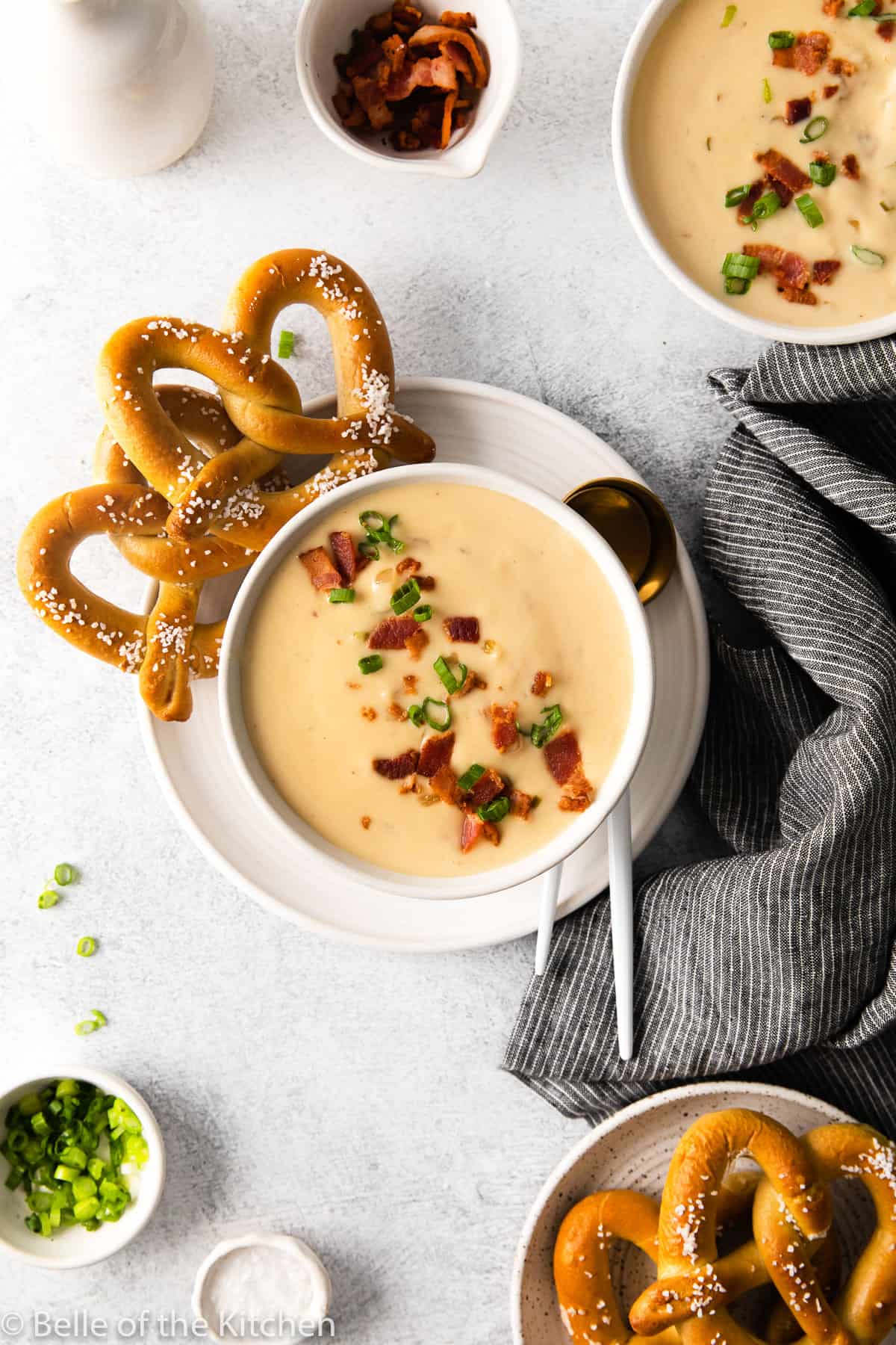a bowl of beer cheese soup next to pretzels