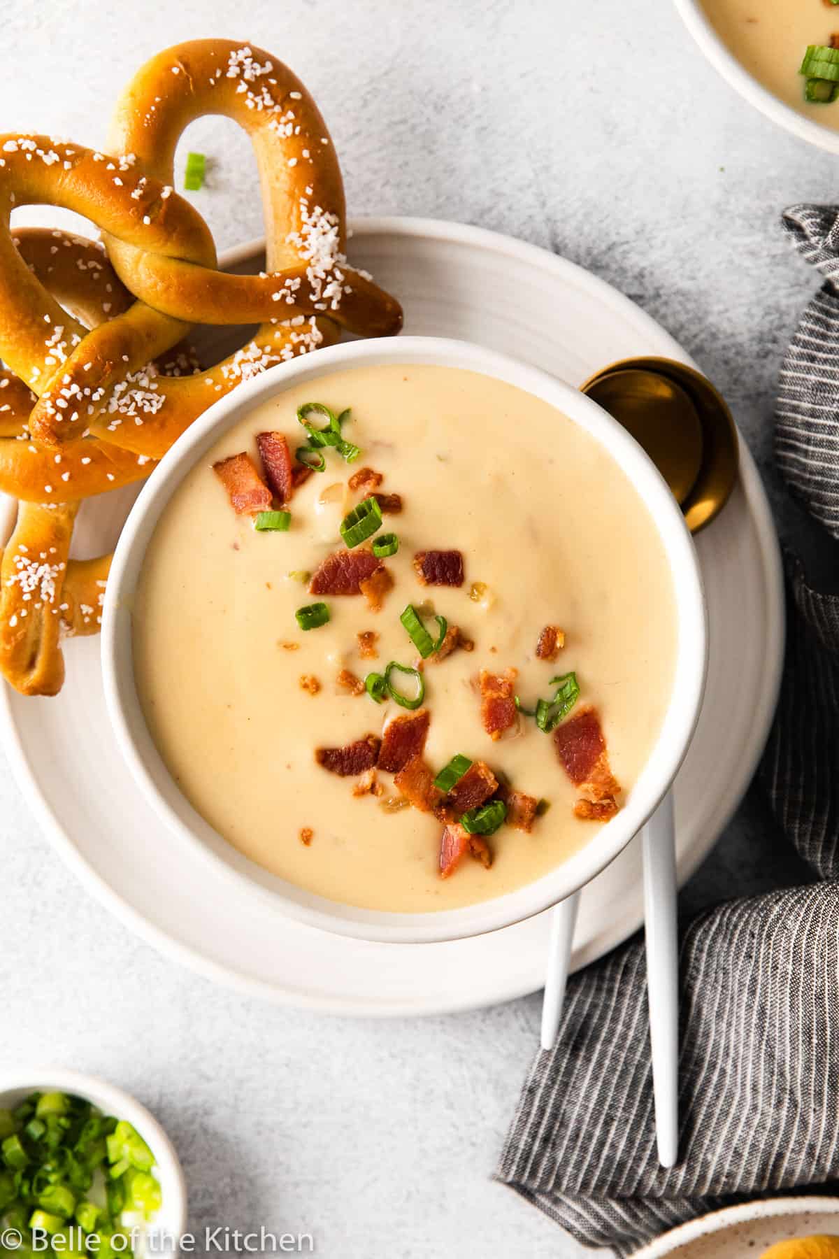 a bowl of soup with a spoon next to pretzels
