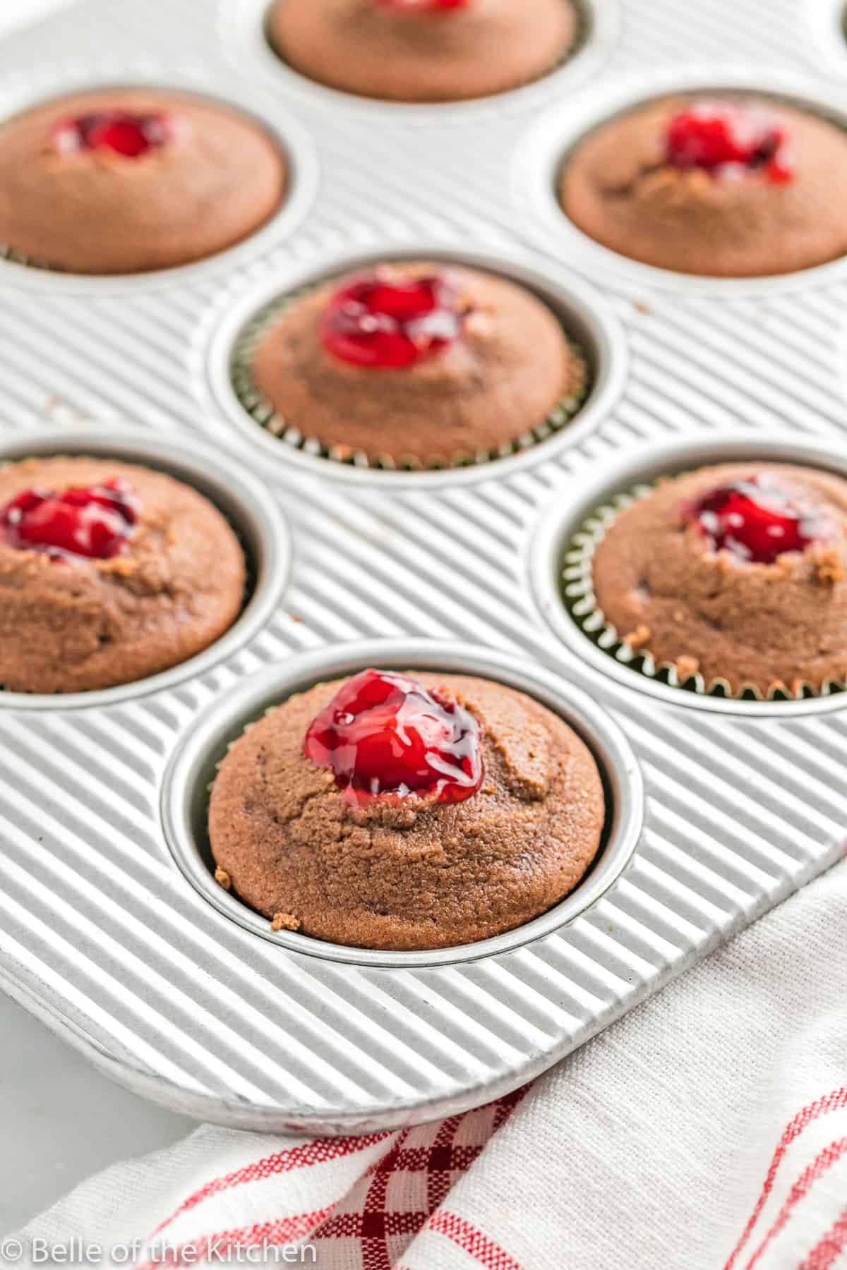 cupcakes in a muffin tin with cherry filling