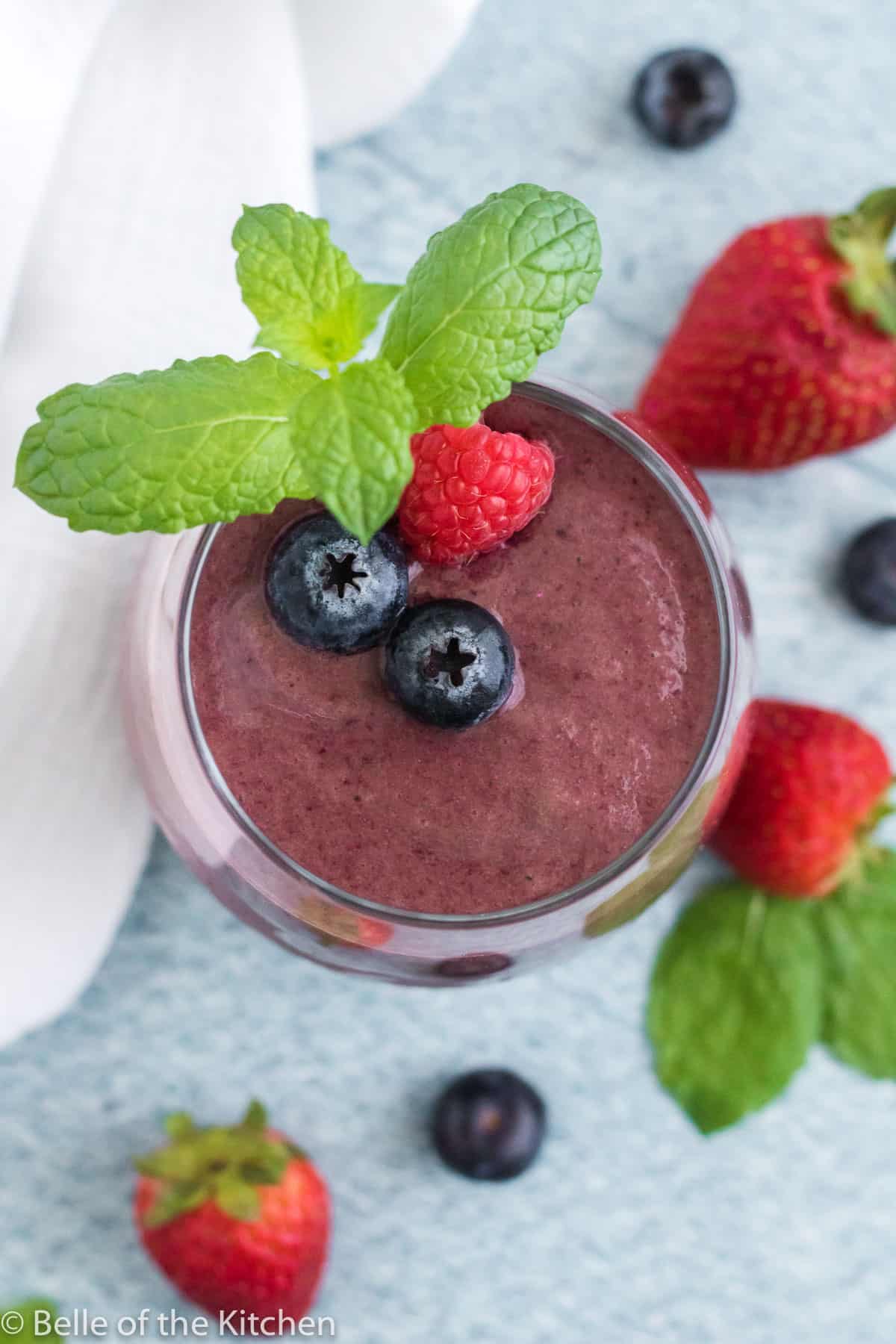 a smoothie in a glass with berries on top