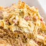 a spoon dishing out chicken cordon bleu casserole with cheese