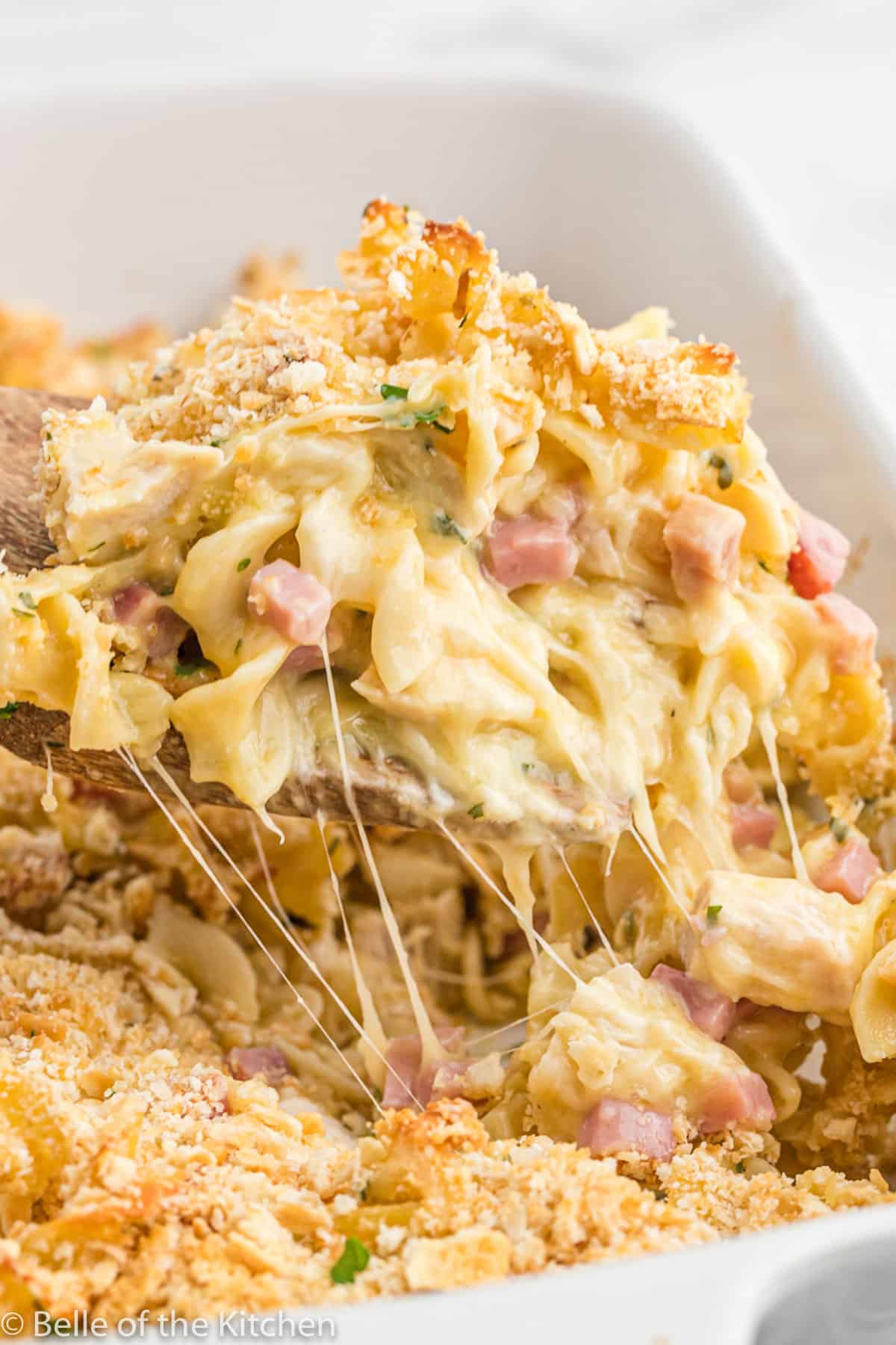 a spoon dishing out chicken cordon bleu casserole with cheese