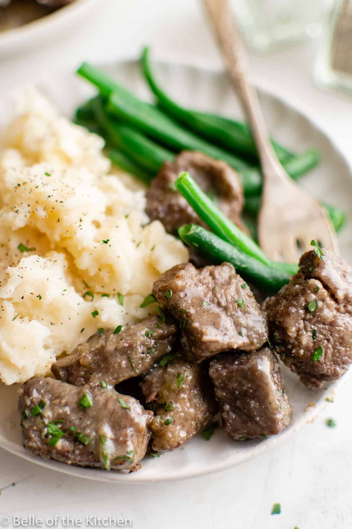 a plate with mashed potatoes, green beans, and steak
