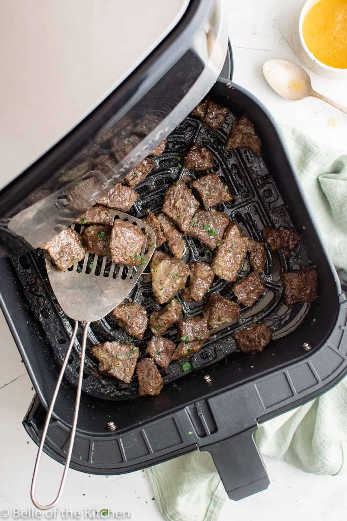 an air fryer basked filled with pieces of steak