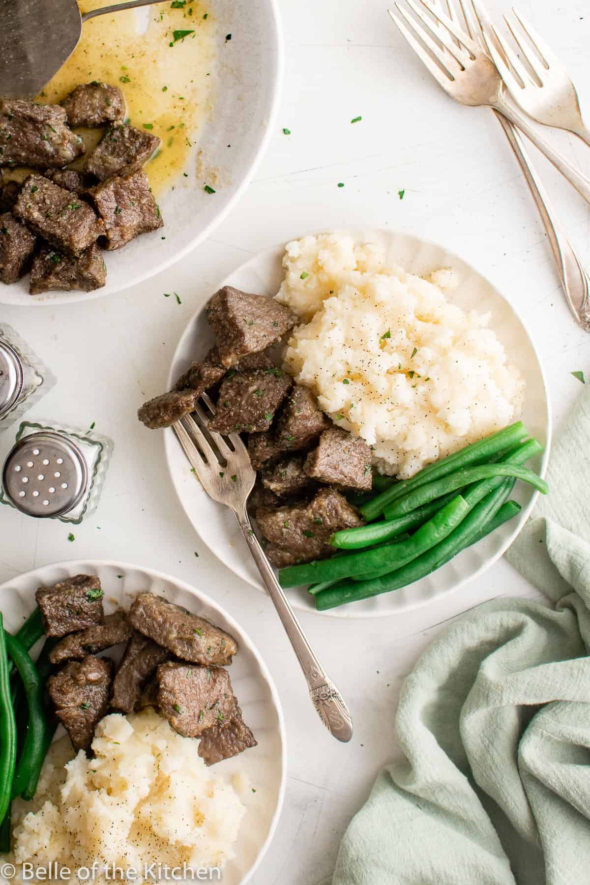 plates with mashed potatoes, green beans, and steak