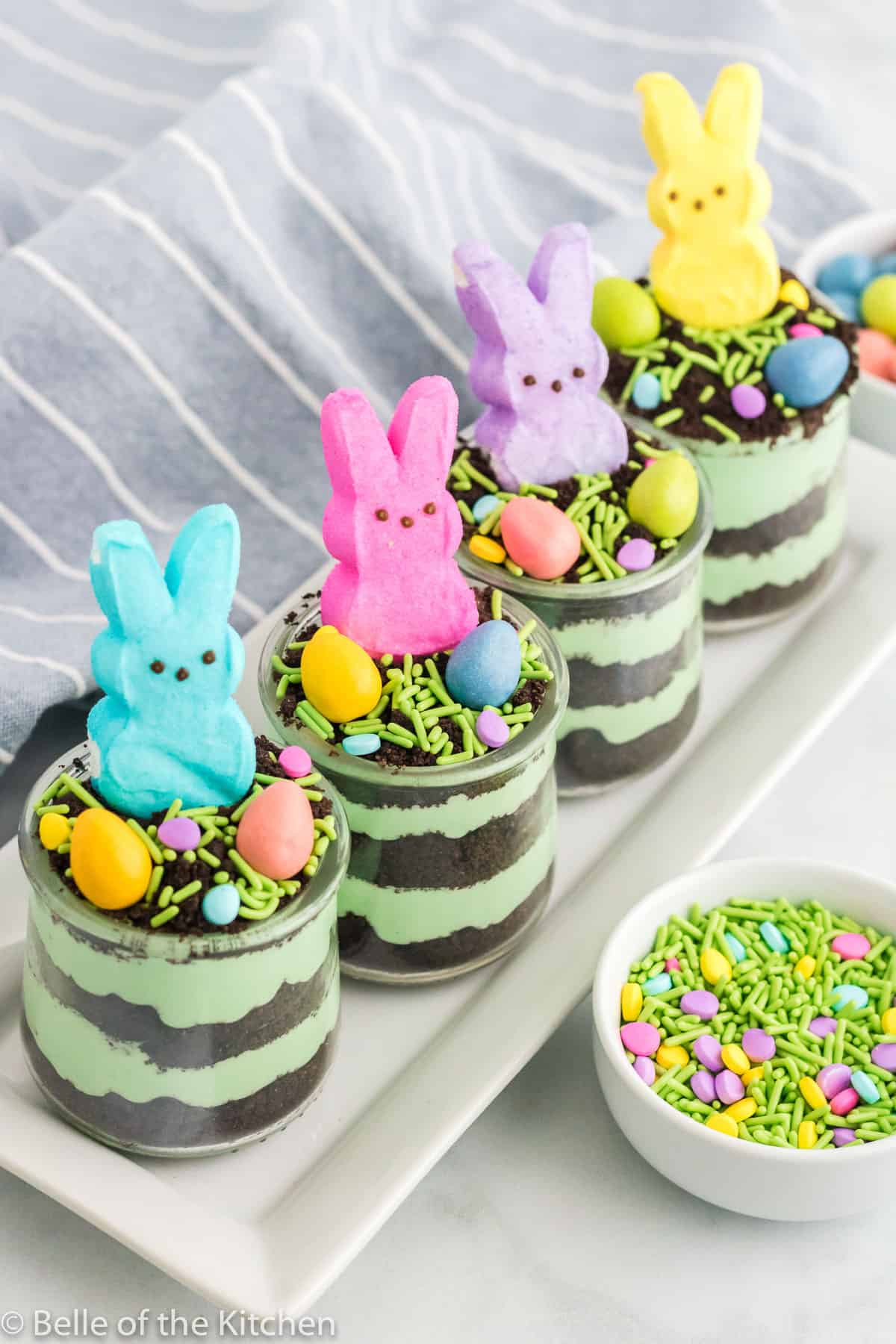 bunny marshmallows in cups of pudding on a white plate