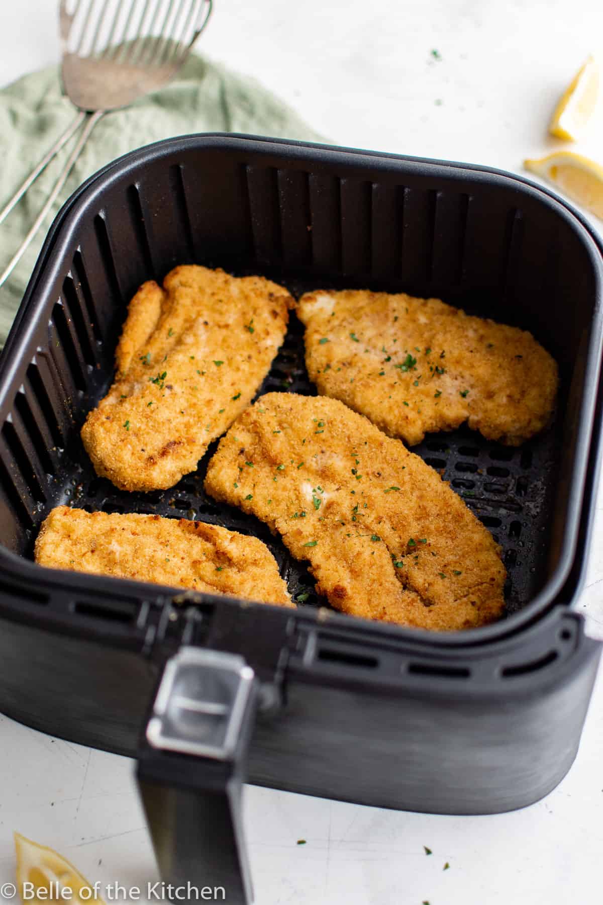air fryer basket holding chicken cutlets