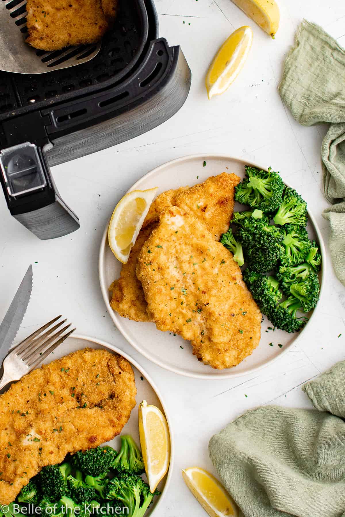 plates of breaded chicken cutlets and broccoli next to an air fryer