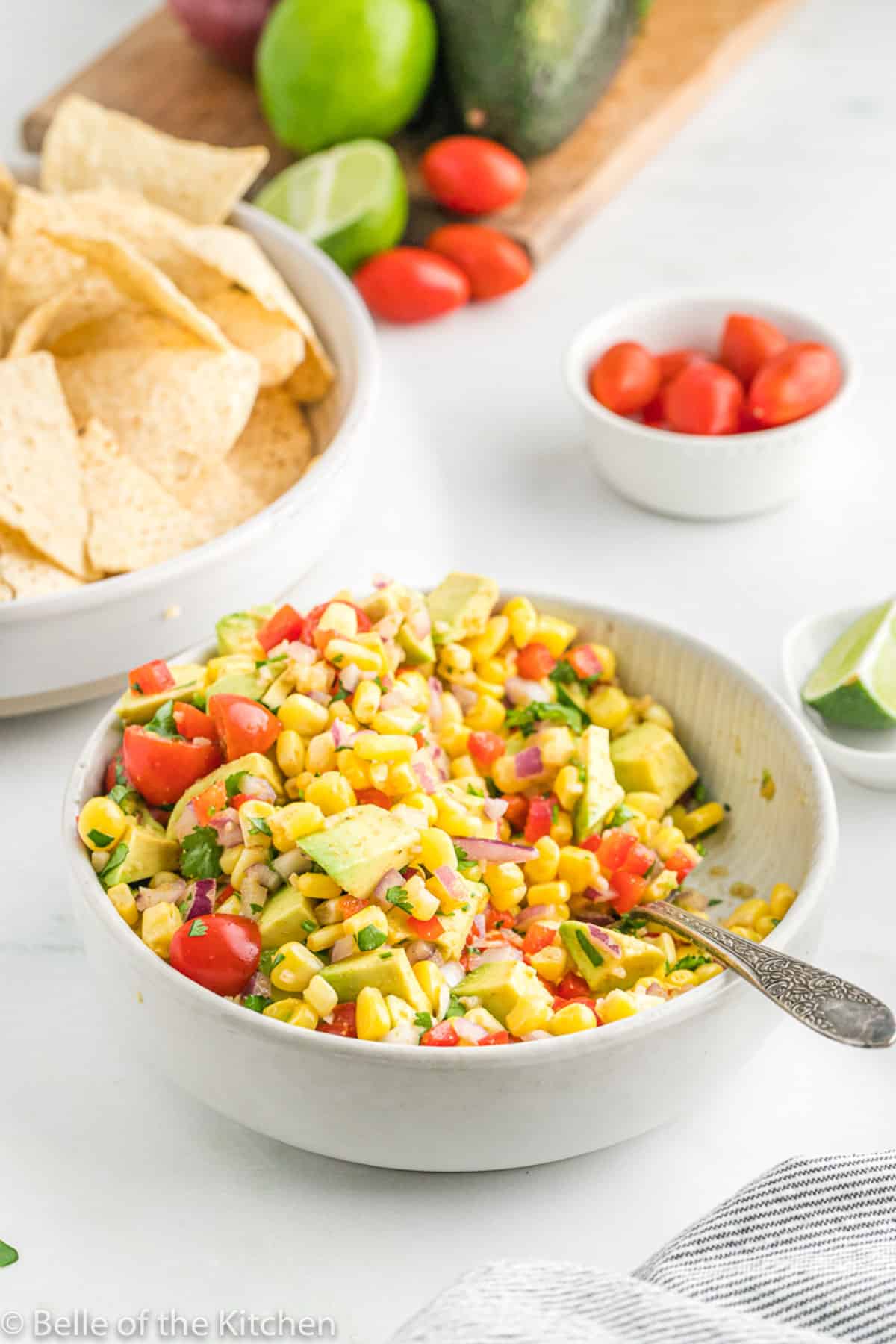 a spoon in a bowl of avocado corn salad