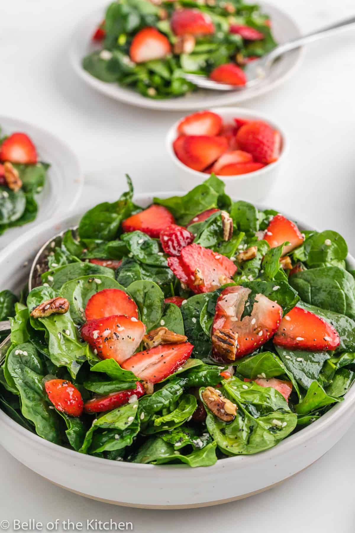 a strawberry spinach salad in a bowl with nuts