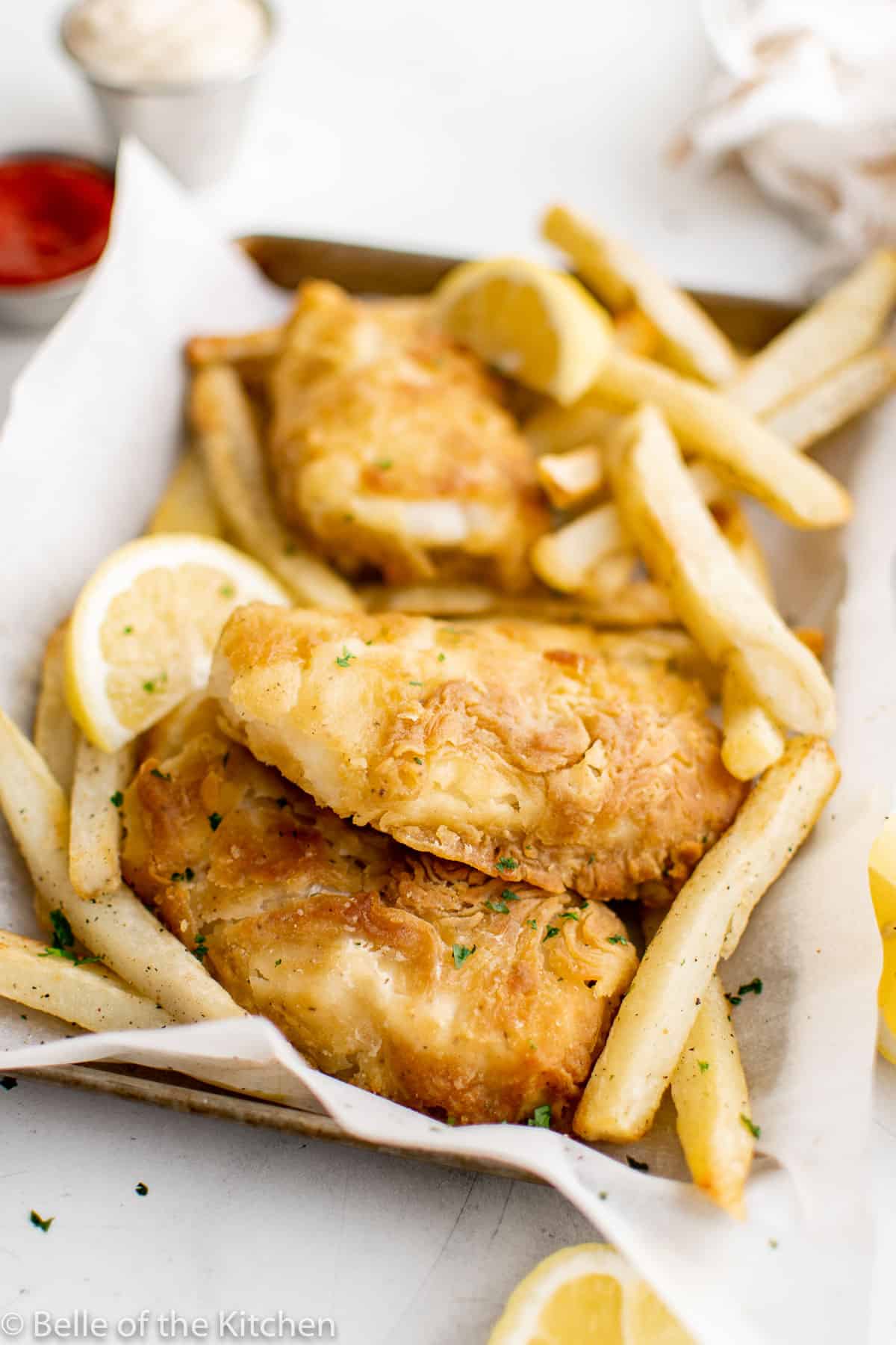 air fried fish on a tray with fries and lemon slices.