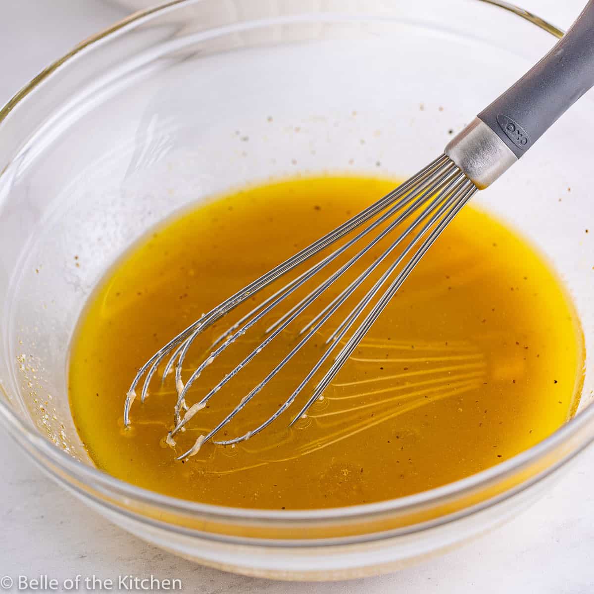 a bowl of dressing with a whisk