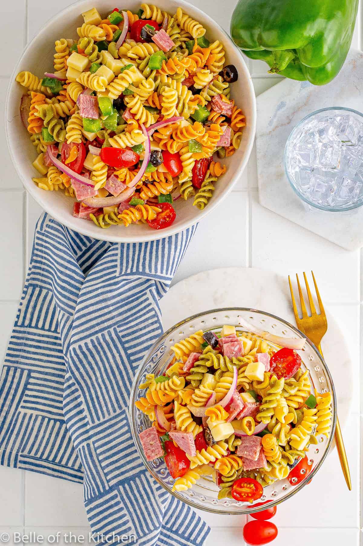 two bowls of pasta salad next to a fork