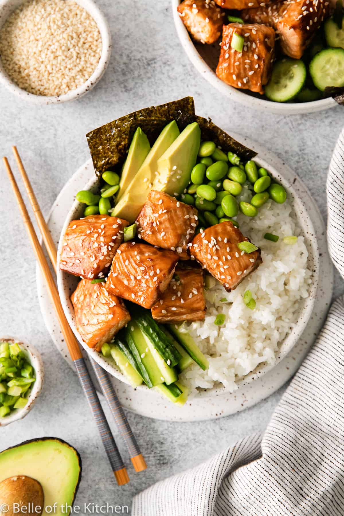 salmon chunks and vegetables on rice in a bowl next to chopsticks