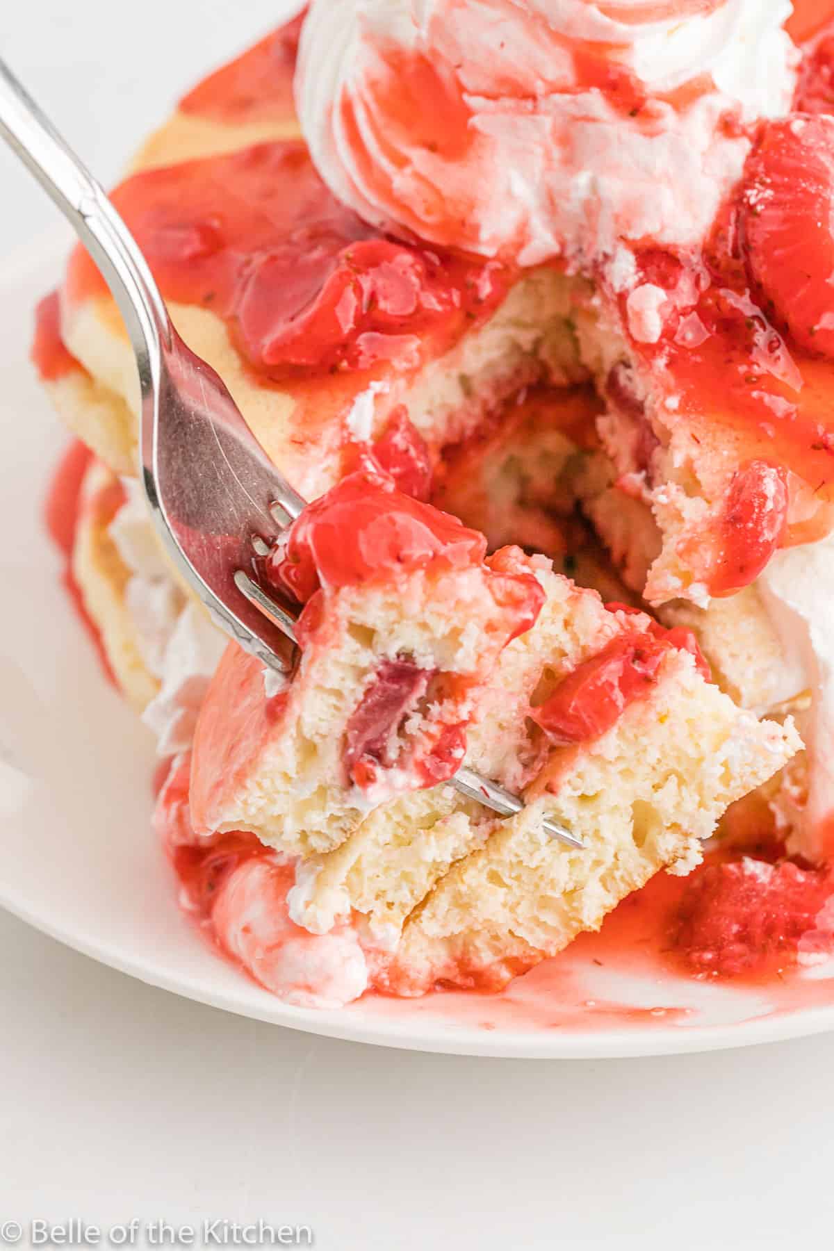 a fork holding sliced pancakes with strawberries