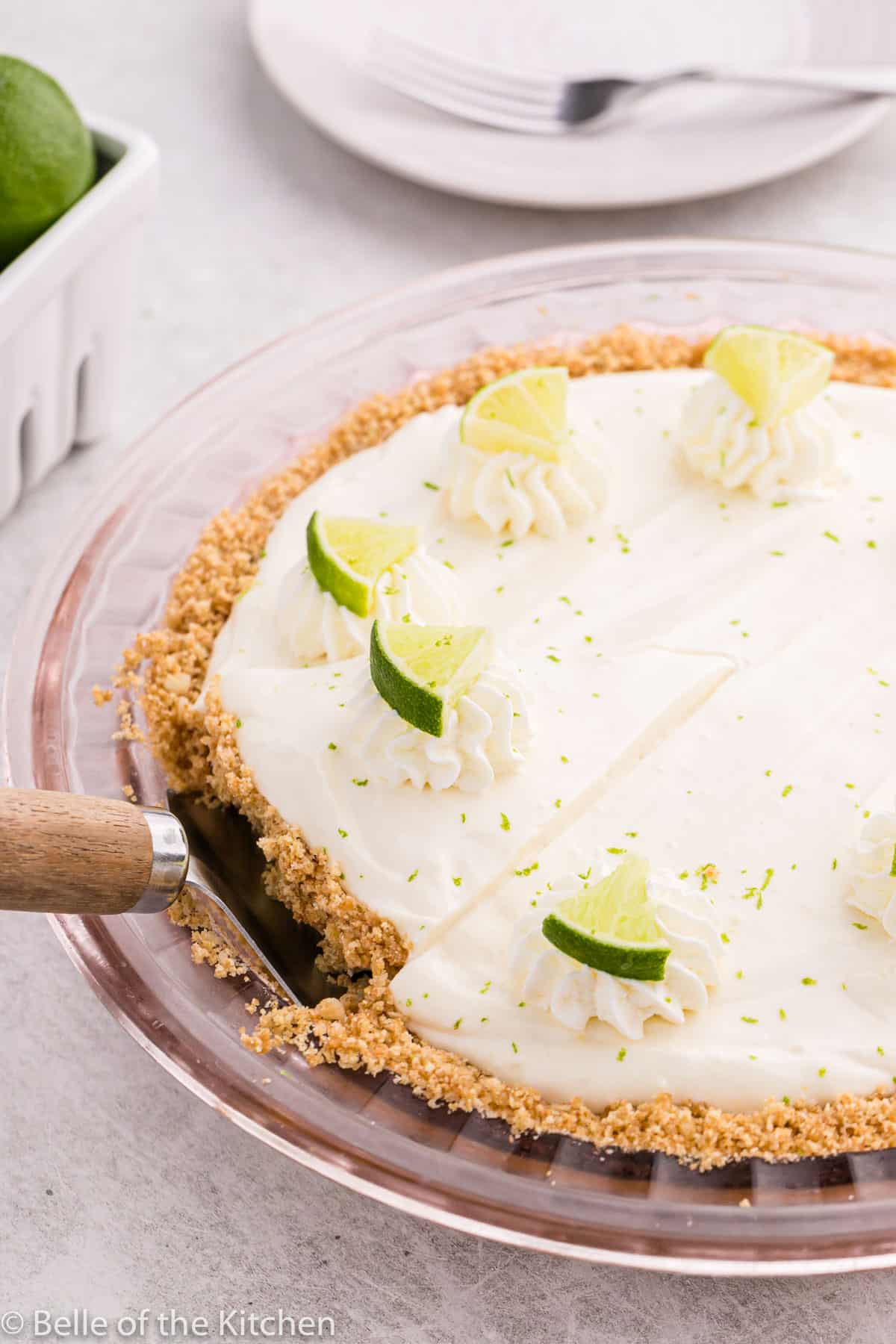 a spatula removing a piece of pie from a plate with limes on top.