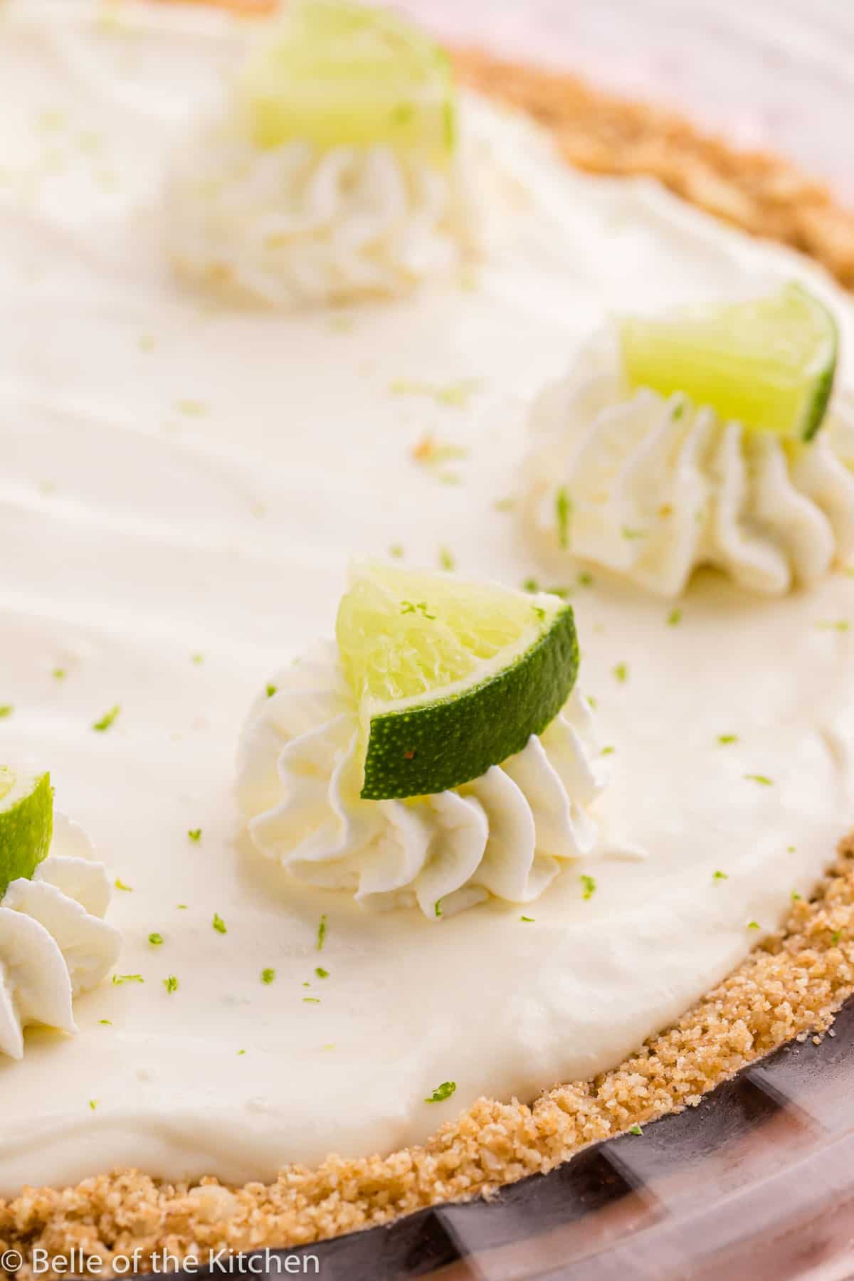 a key lime pie topped with whipped cream and limes.
