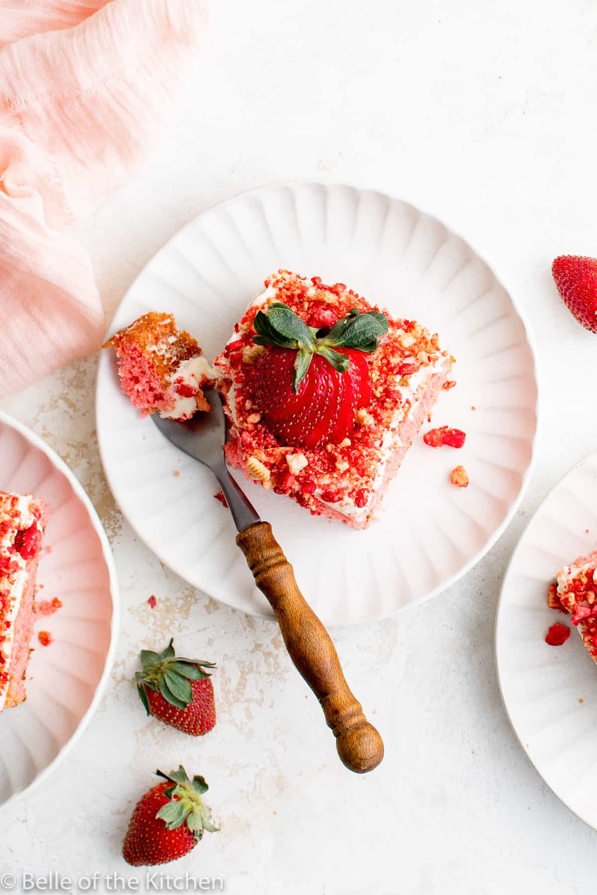 a slice of strawberry cake on a white plate with a fork.