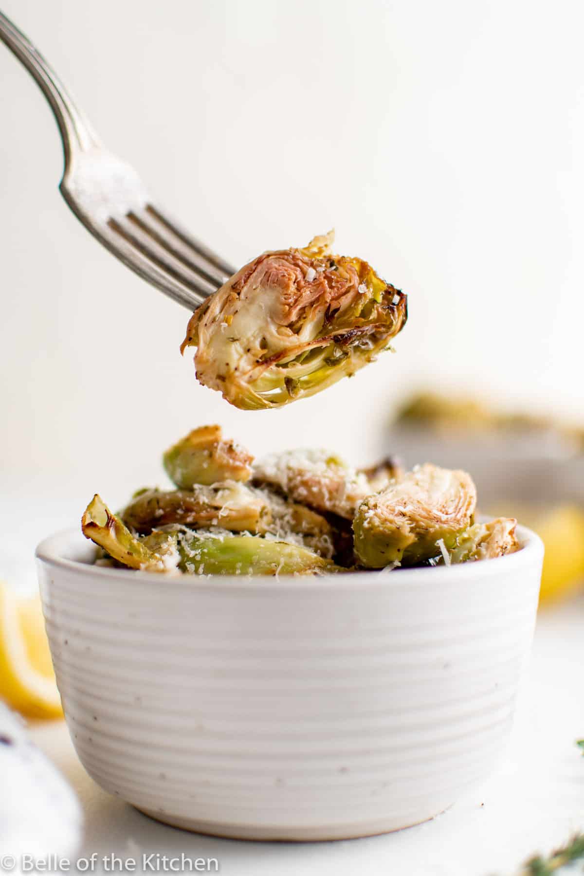 a fork holding a Brussels sprout over a bowl.