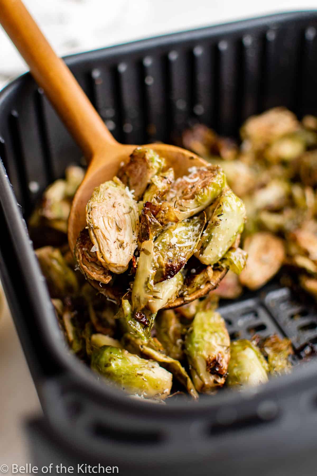 a wooden spoon holding roasted Brussels sprouts.