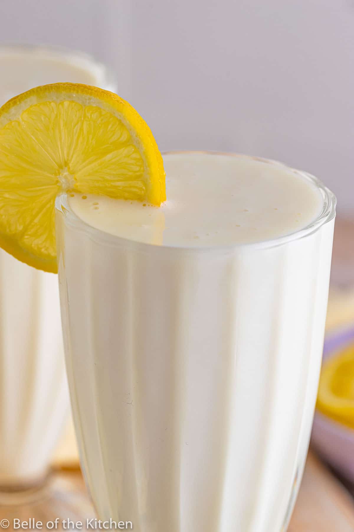 a close up of a glass of frosted lemonade with a lemon slice.