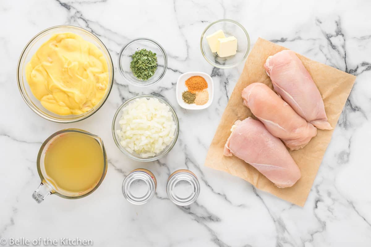 ingredients in bowls and chicken on a cutting board.