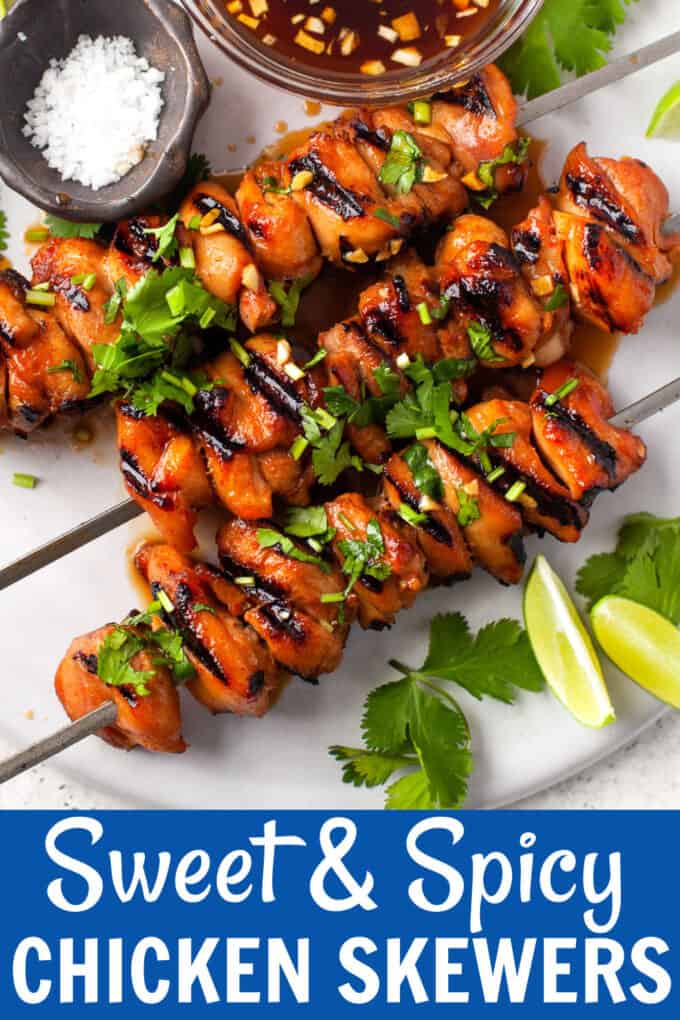 chicken skewers on a marble plate next to bowls of marinade and salt with limes on the side.