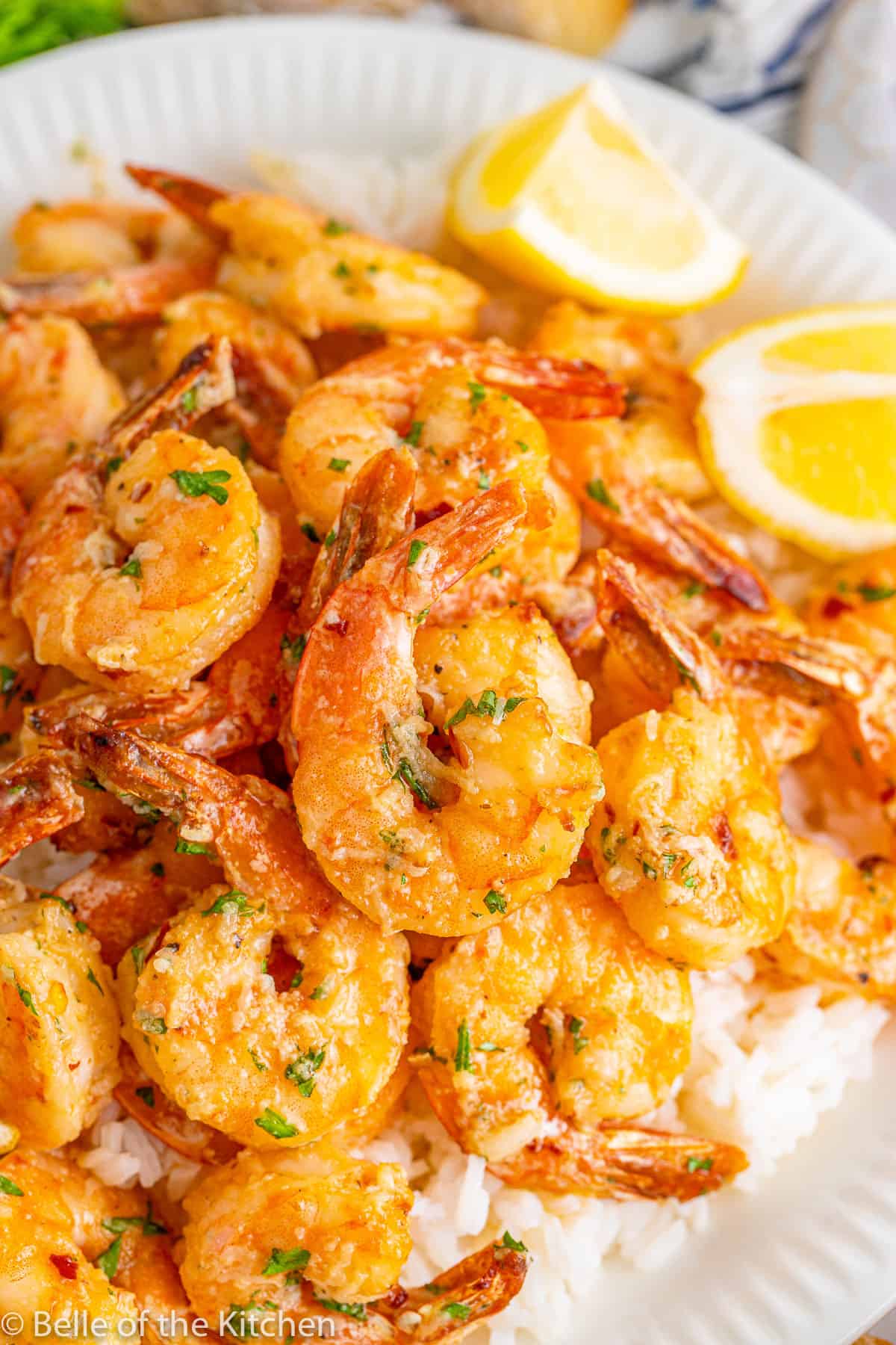 a plate full of rice and shrimp with lemon on the side.