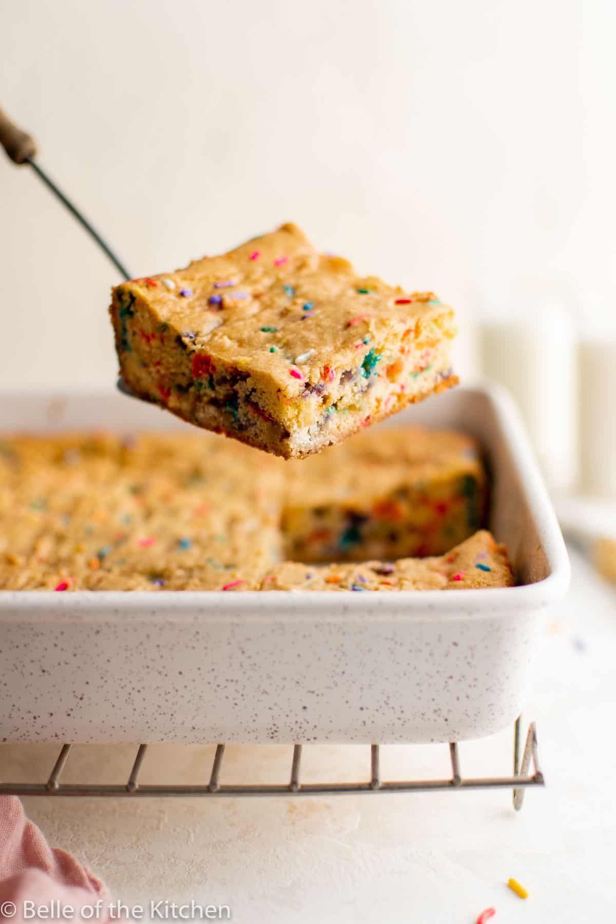 a spatula holding a cookie bar above a baking dish.