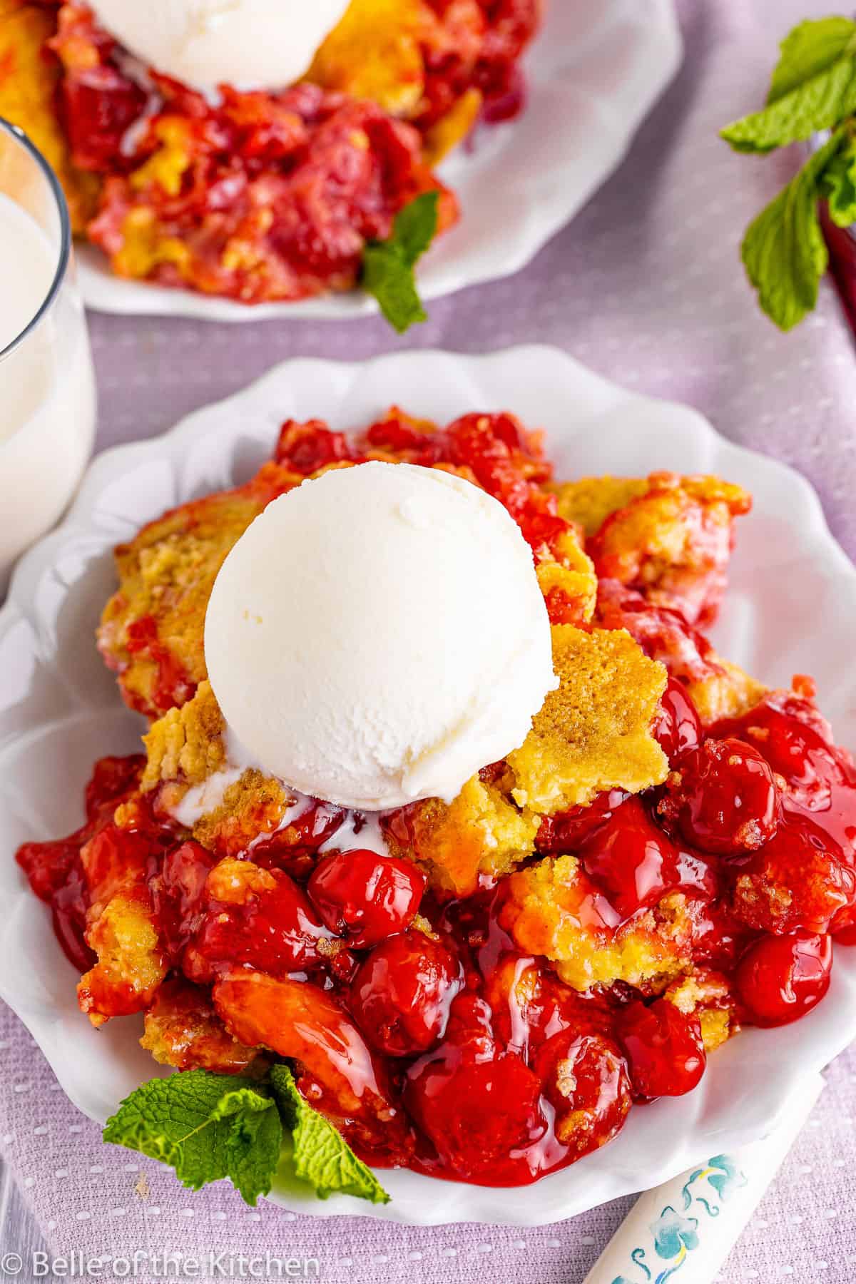 a plate of cherry cobbler with vanilla ice cream on top.