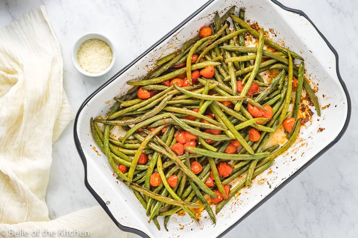 a baking pan of green beans and tomatoes.