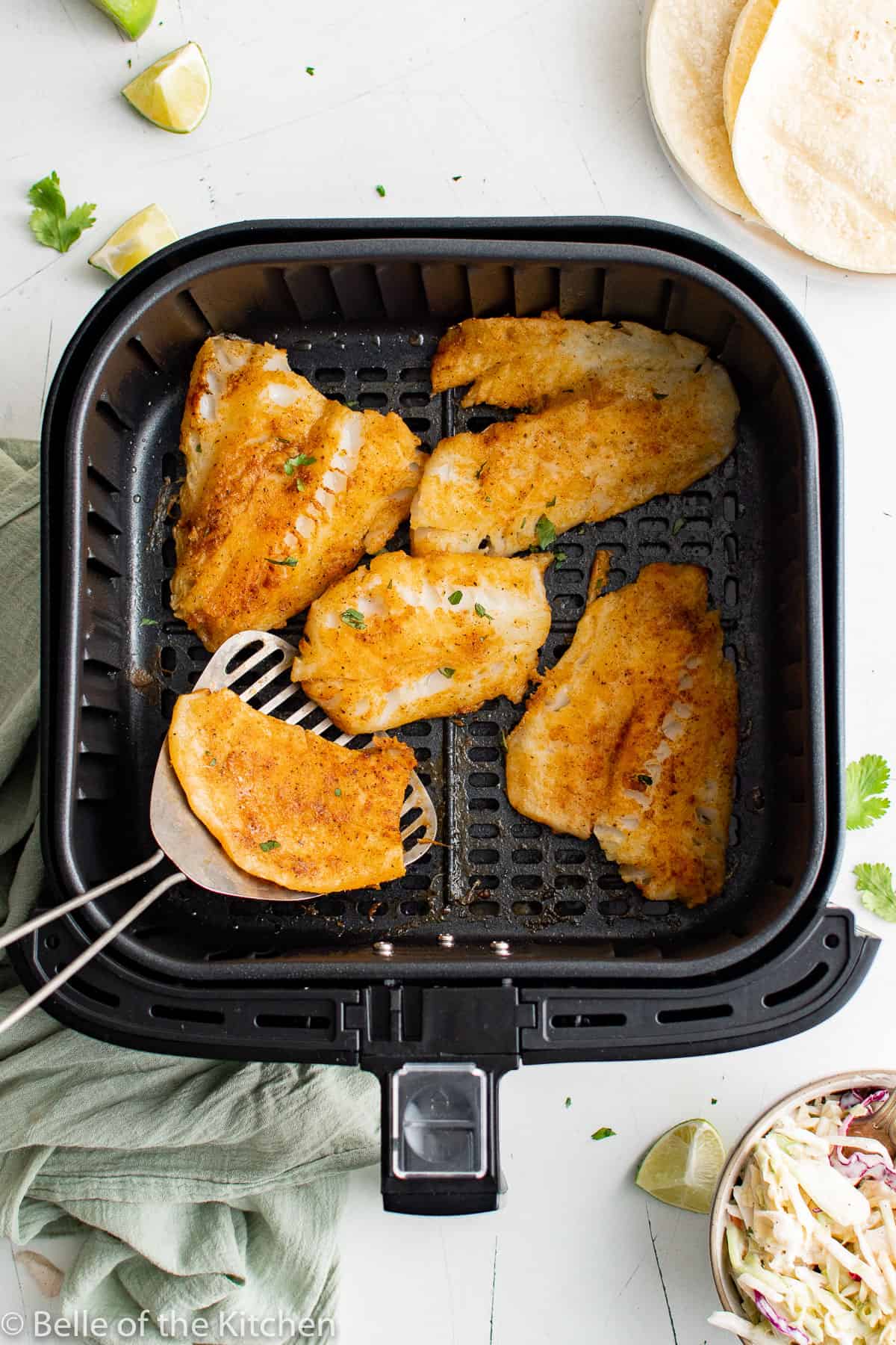 cooked crispy fish in an air fryer basket.