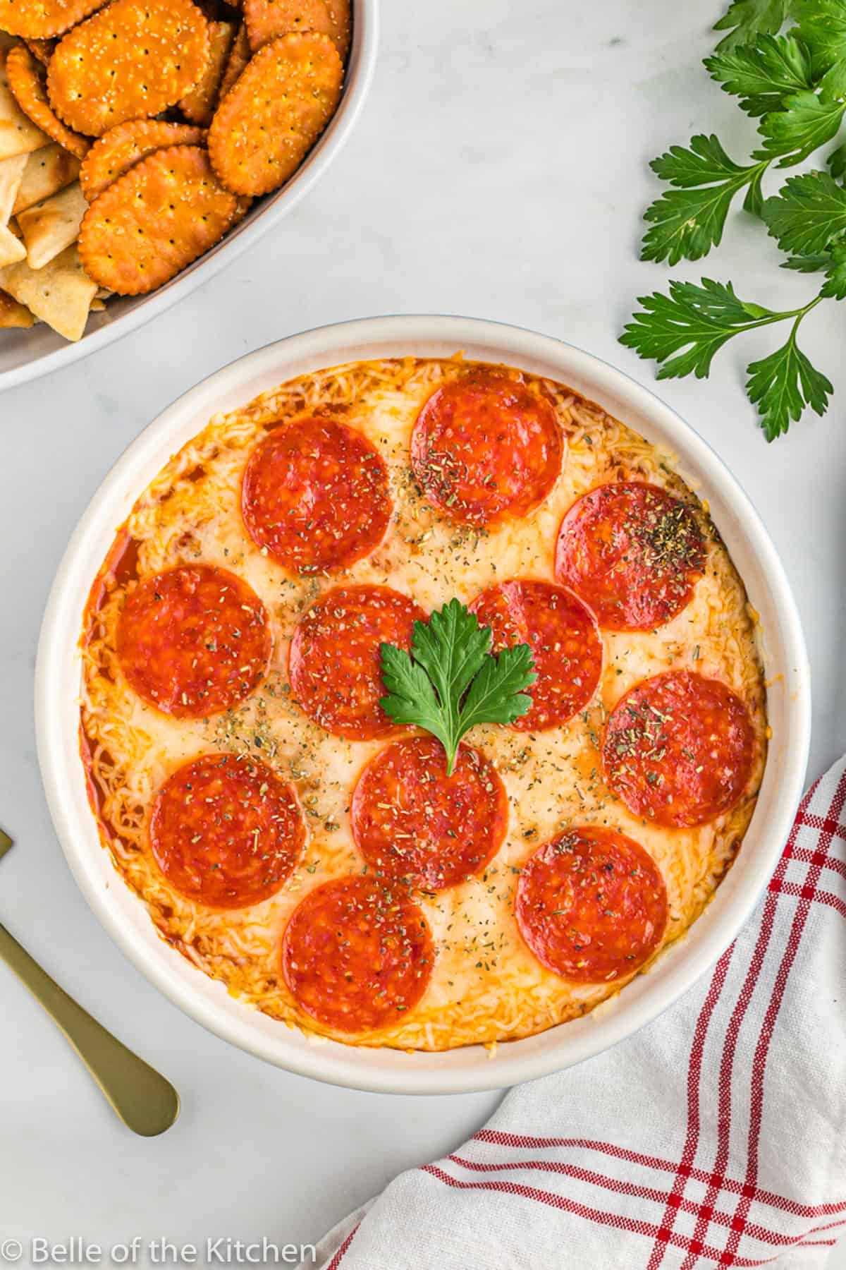 a dish of pizza dip with pepperonis on top.