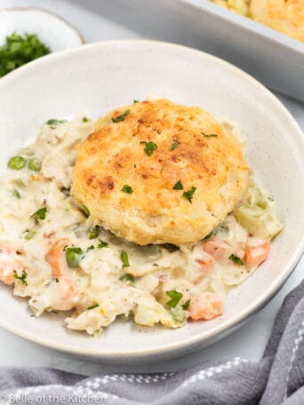 a bowl of chicken with a biscuit on top.