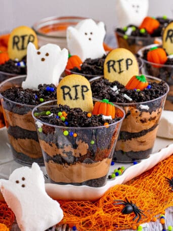 plastic cups full of crumbled Oreos, cookies, ghost marshmallows, and candy pumpkins.