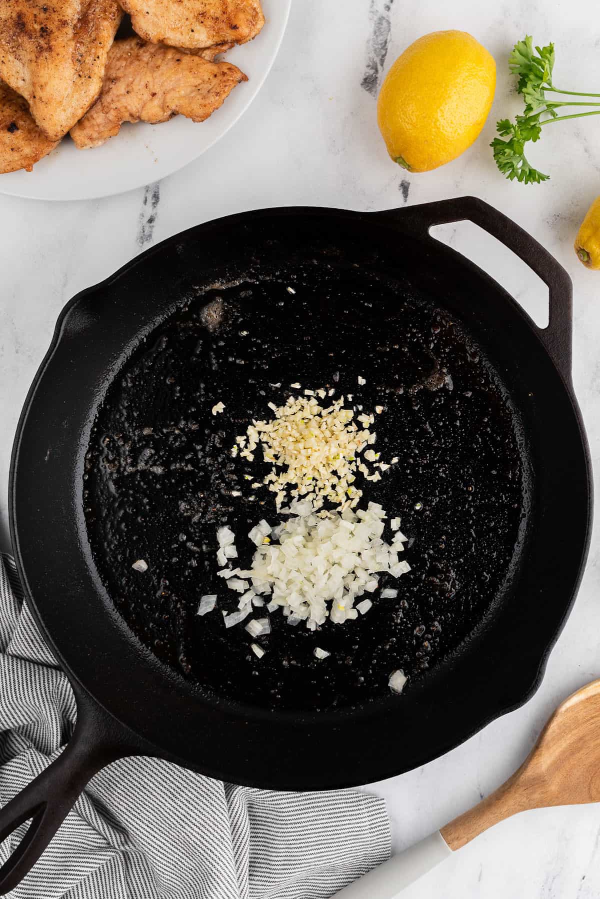 onions and garlic cooking in a black skillet.