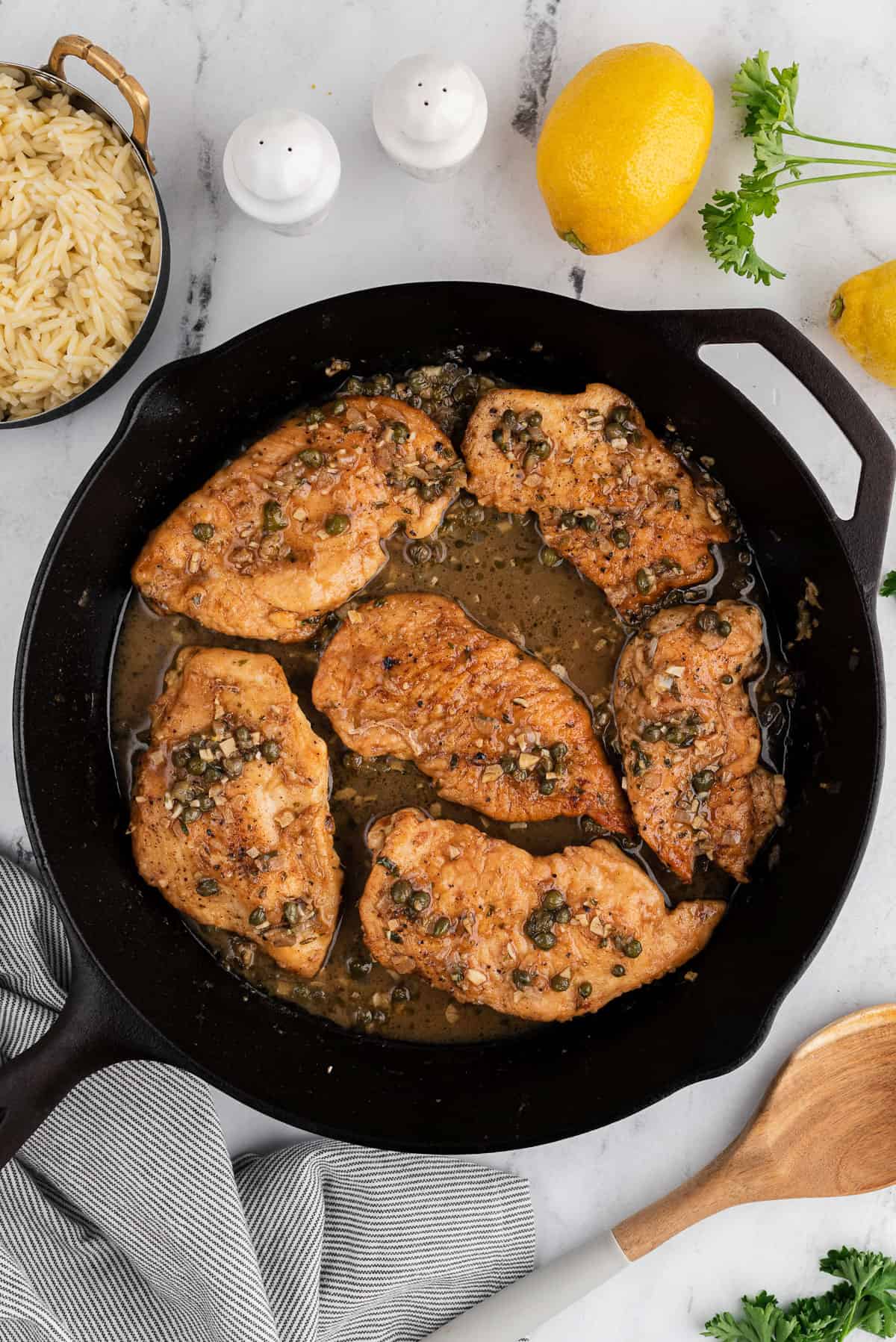 chicken breasts cooking in a black skillet.